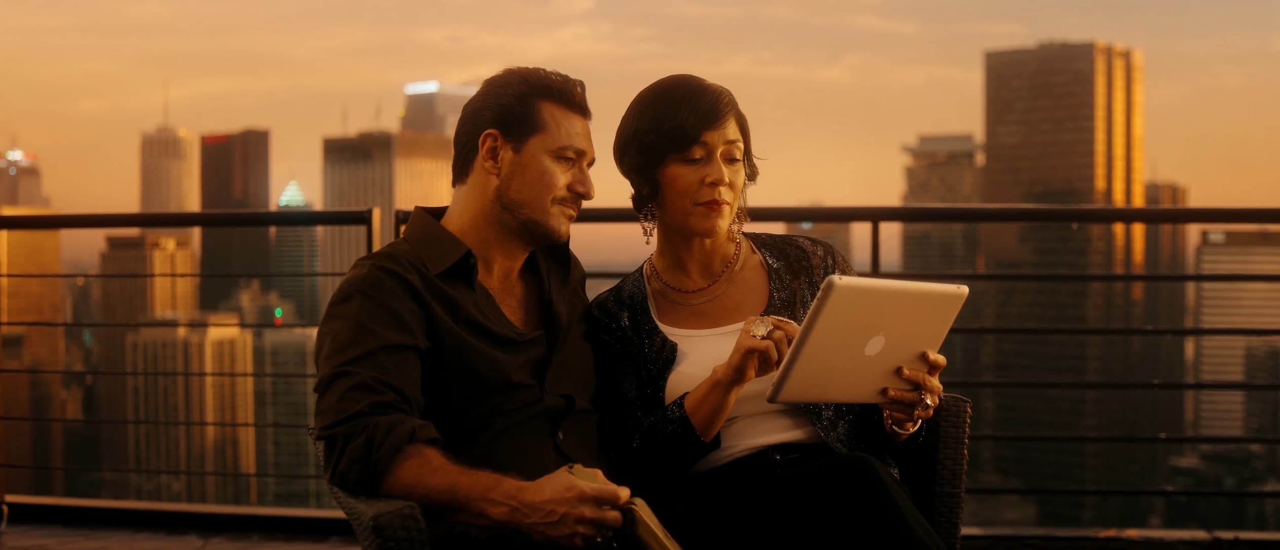 Pareja revisando su plan de inversión en terraza con vista a la ciudad al atardecer — fondos de inversión