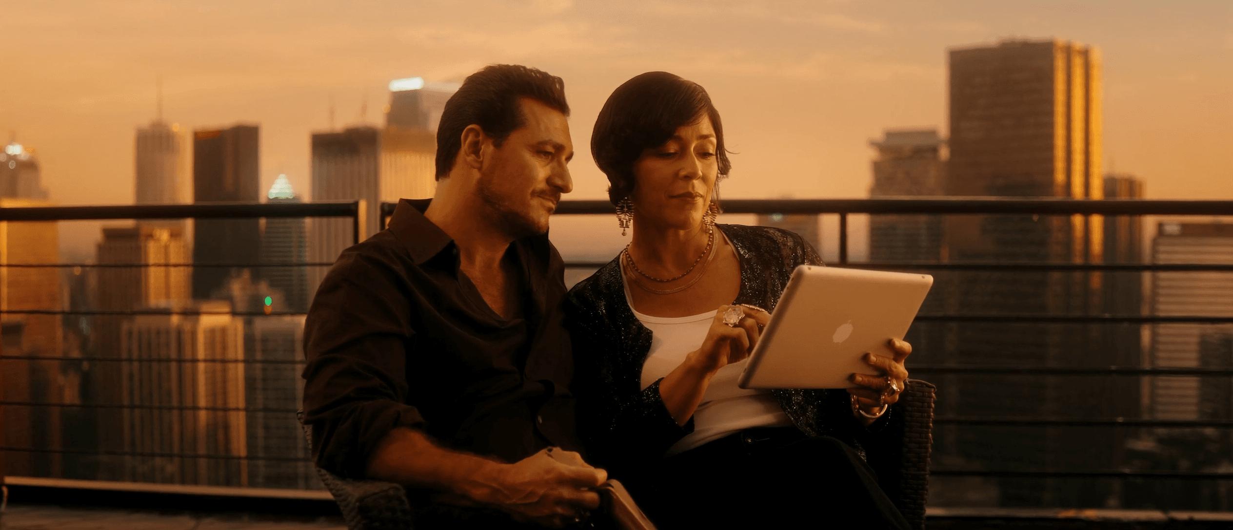 Pareja revisando su plan de inversión en terraza con vista a la ciudad al atardecer — fondos de inversión